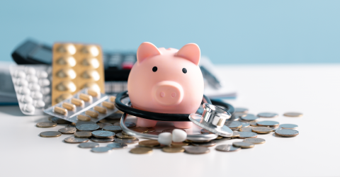 Prinsjesdag; spaarvarken met stethoscoop muntgeld, pillen en een rekenmachine op een blauwe achtergrond